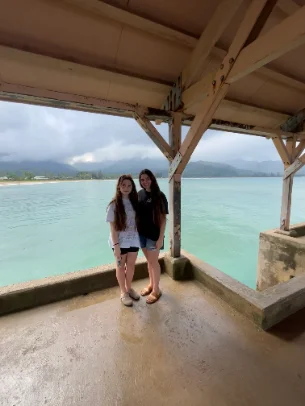 Cailin and a friend on a covered pier above turquoise water