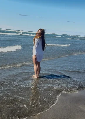 Cailin standing in the ocean waves on a sunny day